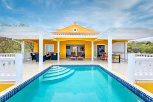 a villa with a swimming pool in front of a house at Coral Estate Rentals in Willibrordus +30 photos