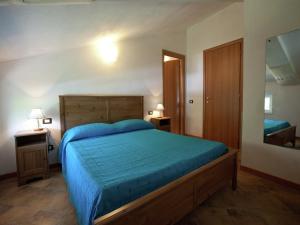 Schlafzimmer mit einem Bett mit blauer Decke und einem Spiegel in der Unterkunft Spacious home surrounded by nature in Sesta Godano