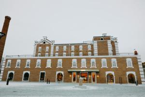a large red brick building in the snow at Pana Unique Semey in Semey