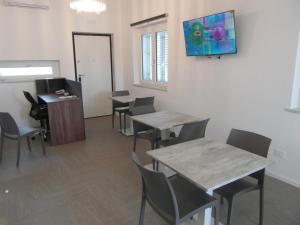 een wachtkamer met tafels en stoelen en een tv aan de muur bij BeB Nido degli Ulivi in Catanzaro