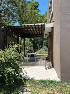 een patio met een picknicktafel onder een pergola bij Jacaranda Mar Azul in Mar Azul