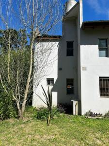 een wit huis met een boom ervoor bij Jacaranda Mar Azul in Mar Azul