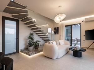 een woonkamer met een witte bank en een trap bij Sav & Leo Mindful Residences in CHQ