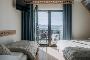 a bedroom with two beds and a balcony with a view at Willa Janowa & SPA in Bukowina Tatrzańska