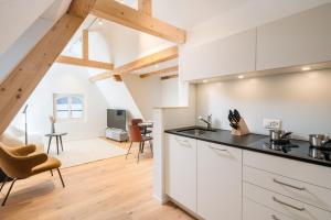 a kitchen with white cabinets and a living room at Apartments Quellenhöfli in Vitznau