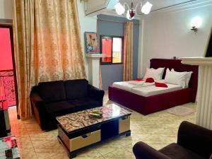 een woonkamer met een bed en een bank bij NGK Hôtel Apartment in Bafoussam