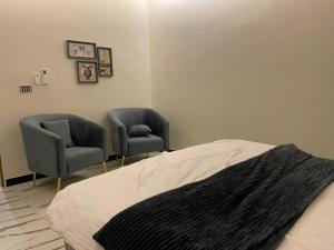a bedroom with two chairs and a bed at ASNB Residences Apartment 2BHK F4 in Multan
