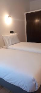 een wit bed met een licht erop bij Lavanda Termas de São Pedro do Sul in Termas de Sao Pedro do Sul