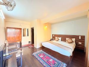 una camera da letto con un letto, una scrivania e una televisione di The OAK Ridge Resort a Gangtok Altre 2 foto