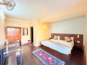 una camera da letto con un letto, una scrivania e una televisione di The OAK Ridge Resort a Gangtok