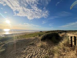 Blick auf einen Strand mit einem Holzzaun in der Unterkunft Escapade à Sainte-Cécile 2 chambres, balcon, plage à 50m in Camiers