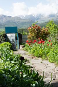 un jardin avec des fleurs rouges devant un bâtiment dans l'établissement Aspet B&B in Tatev, à Tatev