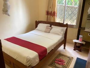 a bedroom with a bed with white sheets and a window at Karmo Suites in Mombasa