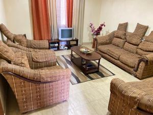 a living room with two couches and a tv at Karmo Suites in Mombasa