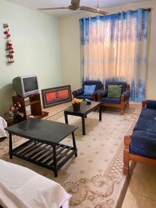a living room with blue couches and a tv at Karmo Suites in Mombasa