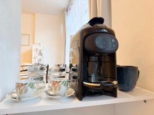 a coffee maker sitting on a shelf with cups at Fiume 34 - bilocale luminoso e moderno a Sondrio in Sondrio
