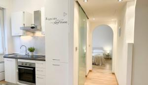 a kitchen with white cabinets and a hallway with a bed at Fiume 34 - bilocale luminoso e moderno a Sondrio in Sondrio