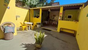 Cette maison jaune dispose d'une terrasse avec une table et des chaises. dans l'établissement Suítes Cantinho do Sossego Ubatuba, à Ubatuba