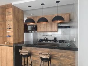 a kitchen with wooden cabinets and a counter with stools at Oceano Residence in Búzios