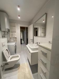 a white bathroom with a toilet and a sink at The Gallery Apartment in Prishtinë +10 photos