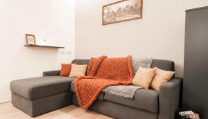 a gray couch with pillows on it in a room at Dusdei 4 - monolocale nel centro di Sondrio in Sondrio