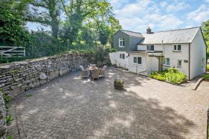 un patio avec une table et des chaises et un mur en pierre dans l'établissement 2 Bed in Advent oc-p6188, à Camelford