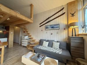 a living room with a couch and a staircase at Studio duplex hyper centre 4 personnes in Le Lioran