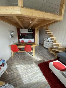 a living room with a wooden table and red chairs at Studio duplex hyper centre 4 personnes in Le Lioran