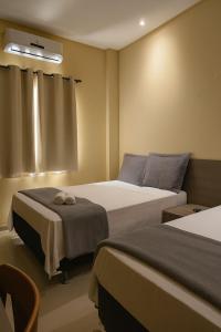 una camera d'albergo con due letti e una finestra di Pousada BarbacoaR a Parnaíba Altre 20 foto