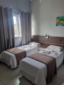 two beds in a hotel room with a window at Miotto Executive Hotel in Navegantes