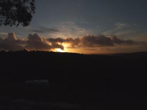 een zonsondergang in een veld met de zon verborgen achter de wolken bij Kurandero Temple in Bensafrim