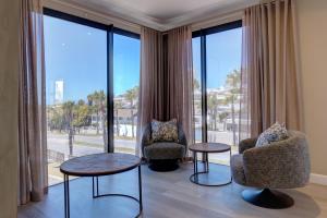 a living room with two chairs and two tables and large windows at Ahoy Boutique Hotel in Gqeberha