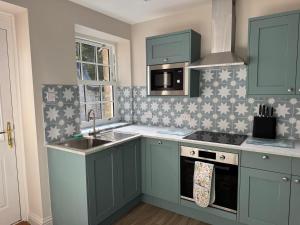 a kitchen with green cabinets and a sink at Spofforth Lodge in Wetherby