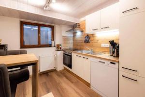 een keuken met witte kasten en een houten tafel bij Ferienwohnung Hans - Hohenpeißenberg mit Gartenblick in Hohenpeißenberg