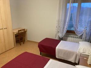 a bedroom with a bed and a window and a desk at La Villa Di Zio Pino in Camerino