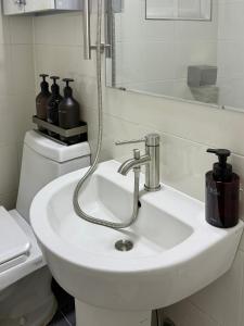 ein weißes Badezimmer mit Waschbecken und Spiegel in der Unterkunft NEW Stay Rombus in Seoul