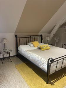 a bedroom with a bed with two yellow pillows on it at Hôtel Le Saint Martin in Sablé-sur-Sarthe