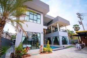 a large white house with a pool and palm trees at บ้านบรรยากาศ พูลวิลล่าชะอำ in Ban Bo Prakhon
