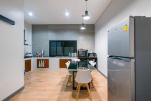 a kitchen with a table and a refrigerator at บ้านบรรยากาศ พูลวิลล่าชะอำ in Ban Bo Prakhon