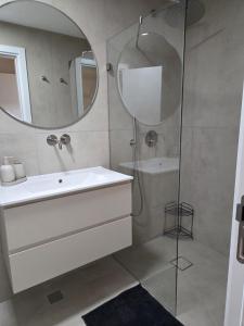 a bathroom with a sink and a shower with a mirror at Atalya Suite in Eilat