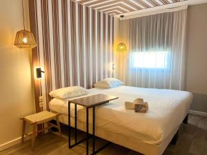 een slaapkamer met een bed met een tafel en een raam bij ibis Styles Nimes Gare Centre in Nîmes