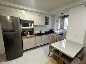 une cuisine avec un réfrigérateur en acier inoxydable et une table dans l'établissement Modern Apartment 500m from Beach, à Barra Velha