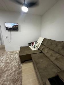 - un salon avec un canapé brun et une télévision dans l'établissement Modern Apartment 500m from Beach, à Barra Velha