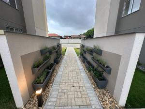 une passerelle avec des plantes en pot sur le côté d'un bâtiment dans l'établissement Modern Apartment 500m from Beach, à Barra Velha