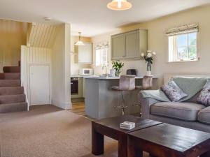 een woonkamer met een bank en een keuken bij The Stables in Whissendine