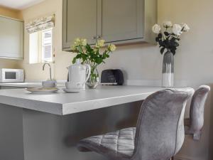 een aanrecht met een vaas met bloemen en een stoel bij The Stables in Whissendine