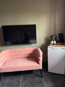 ein rosa Sofa vor einem Flachbildfernseher in der Unterkunft Iosono by Moniek in Geel