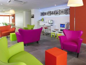 une salle d'attente avec des chaises colorées et une table dans l'établissement Ibis Styles Nivelles, à Nivelles