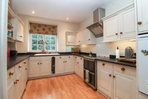 a kitchen with white cabinets and black counter tops at Waterloo Mill Cottage in Wotton under Edge +15 photos
