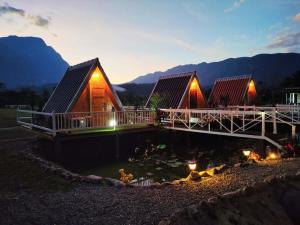 a couple of houses with a pond in front of them at Western View Chiangdao Camping in Chiang Dao
